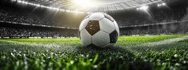 Wet black-and-white soccer ball resting on green grass under bright stadium lights